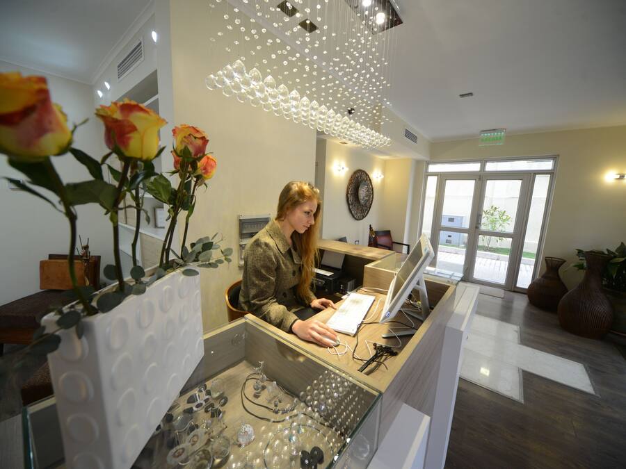 A reception desk with a woman working, surrounded by decorative glassware and vases.