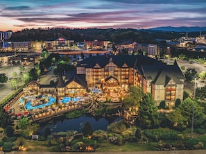 A large hotel with a swimming pool, outdoor dining area, and a well-maintained garden.