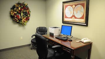 A conference room with a desk, computer, phone, and a framed map on the wall.