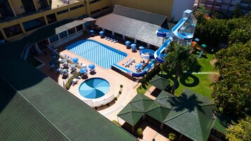 Una piscina techada, una piscina al aire libre, sombrillas