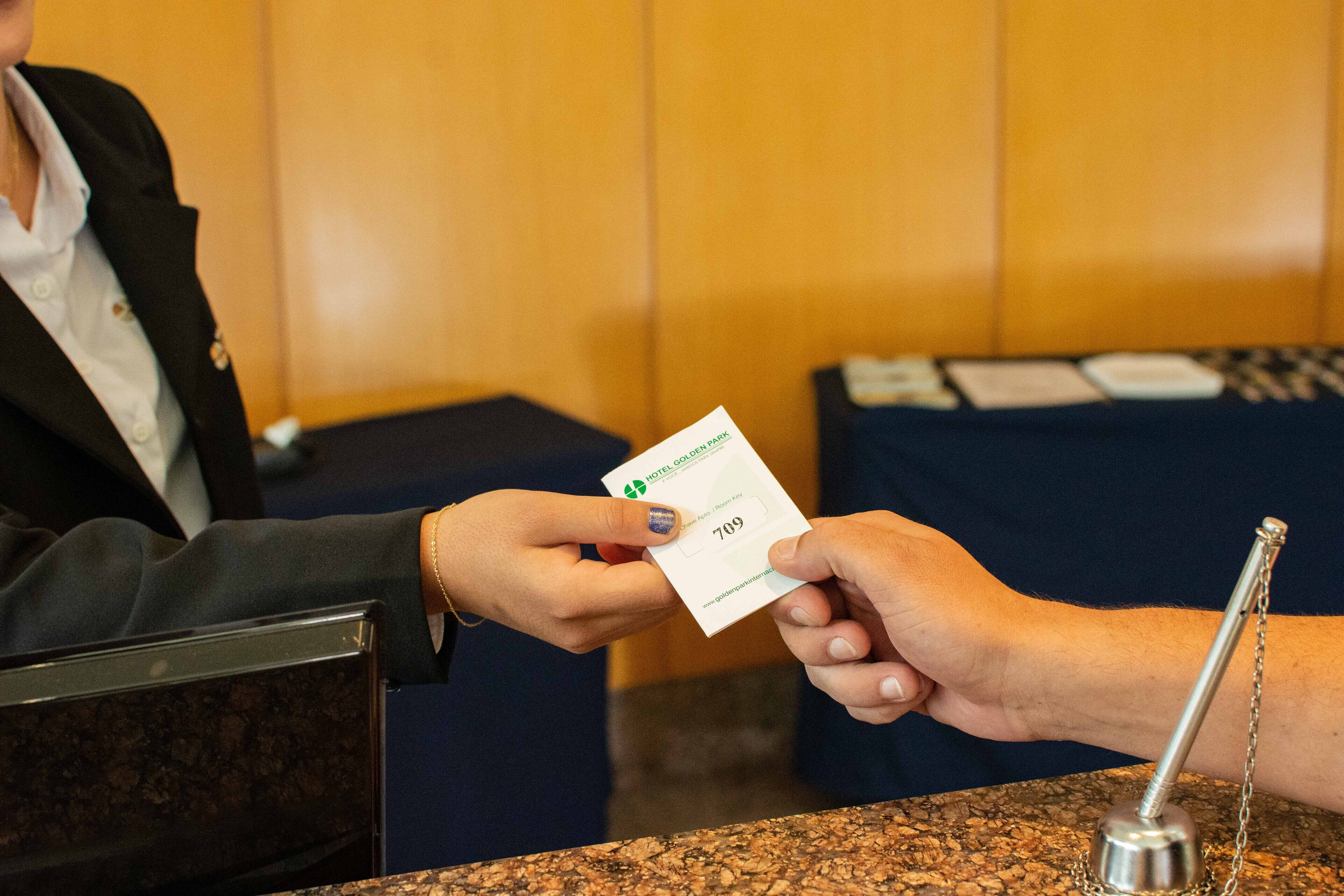 A person receiving a hotel key card from a receptionist.