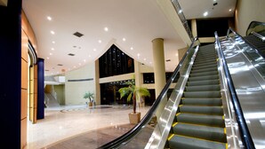 An indoor area with an escalator, a palm tree, and a staircase. - Hotel Golden Park Internacional Foz & Convenções By Nacional Inn (Foz do Iguaçu)