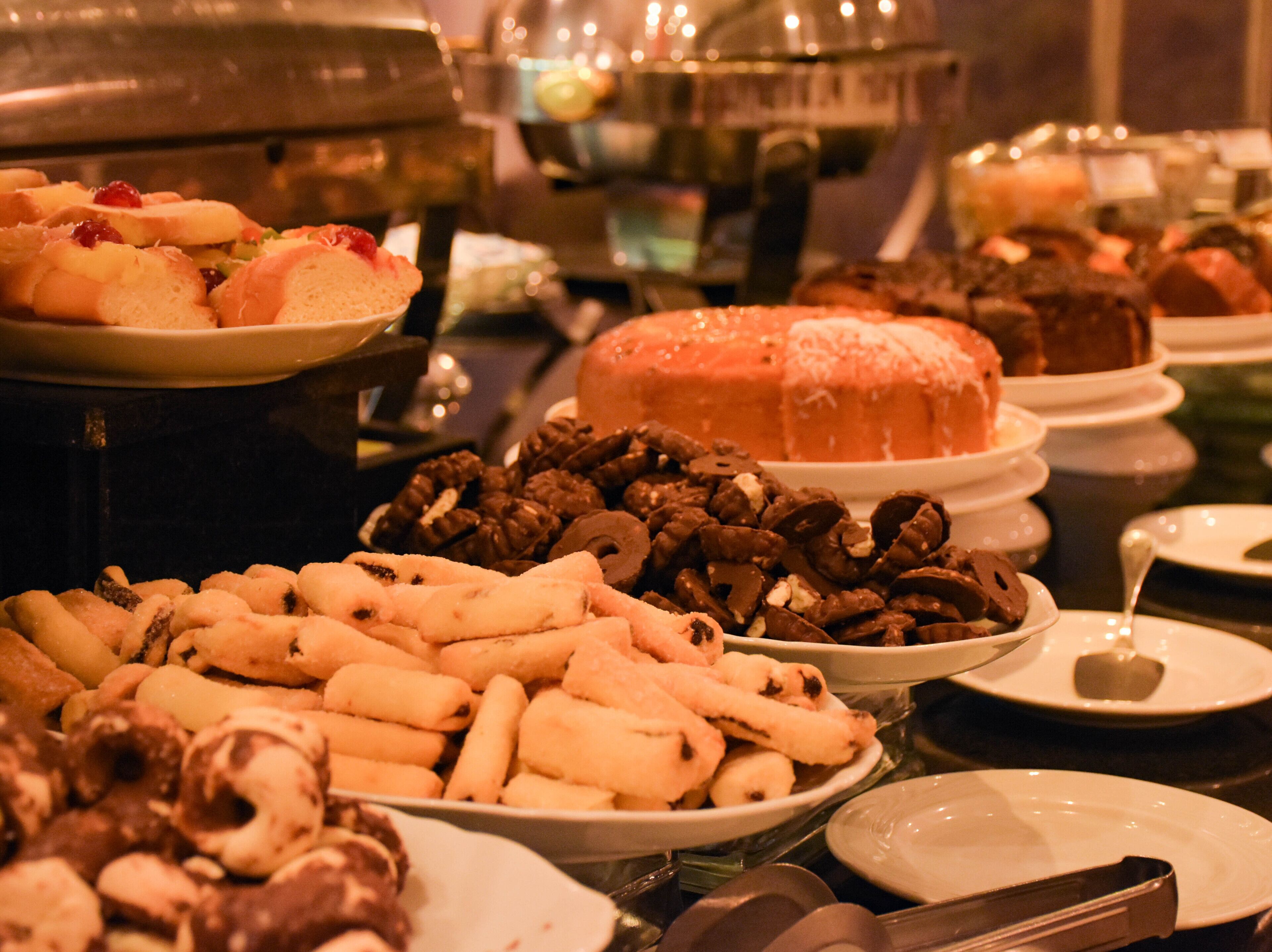 A buffet with various food items including cakes, pastries, and fruits.