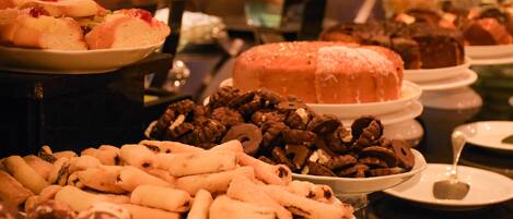 A buffet with various food items including cakes, pastries, and fruits.