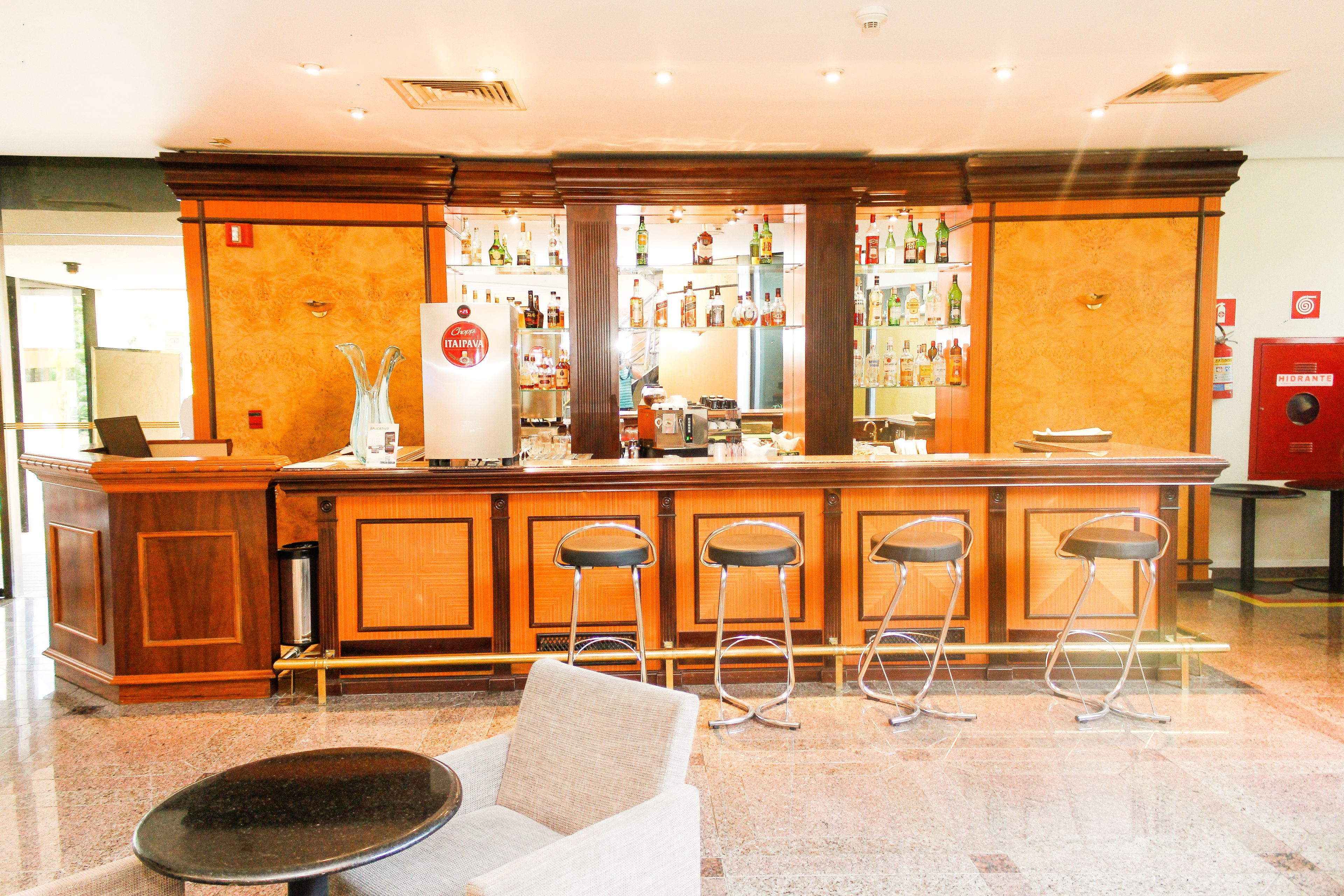 Eine Bar mit Holztresen, Barhocker und einer Sitzecke mit rundem Tisch und Stühlen.