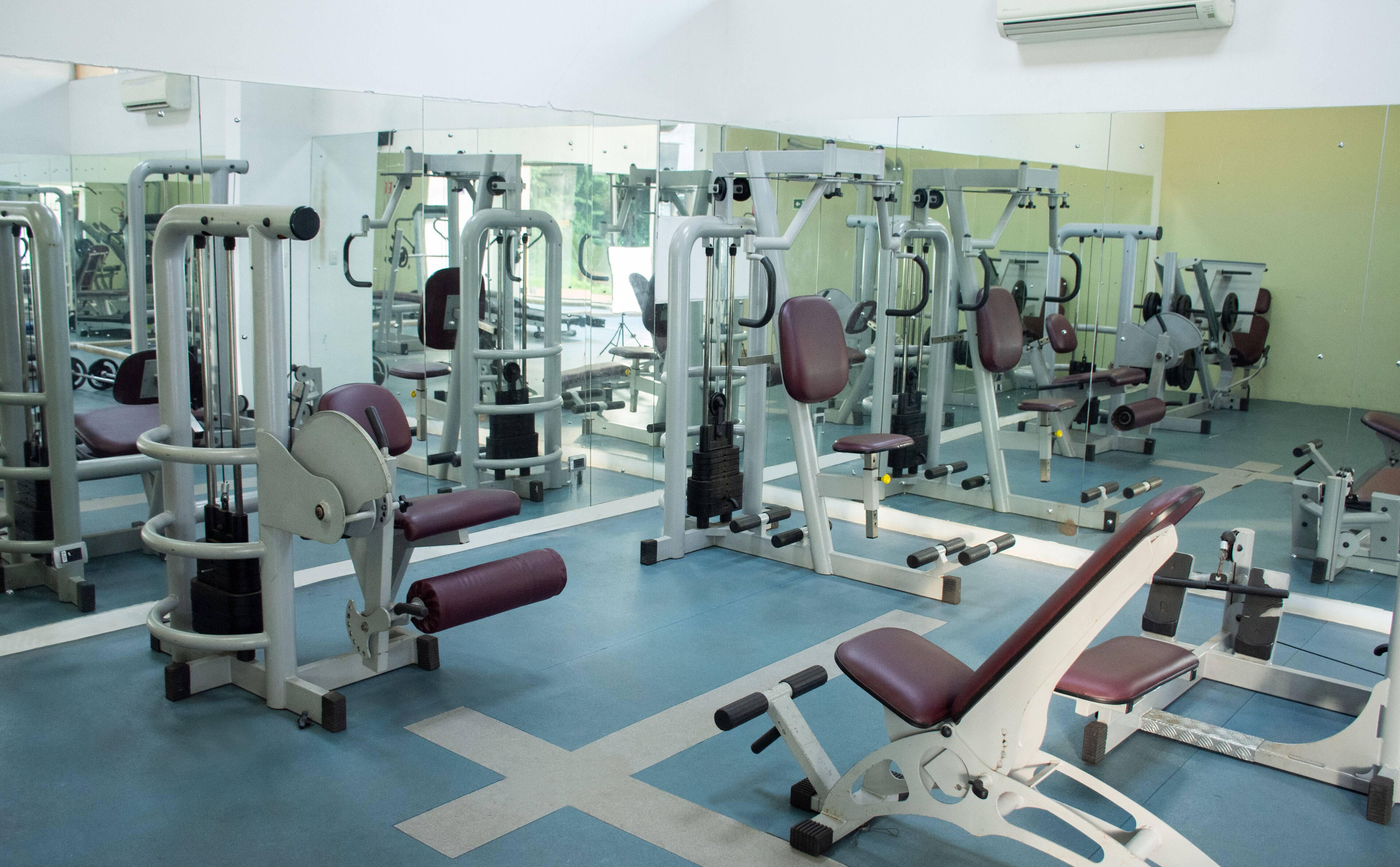 A gym with various exercise equipment, mirrors, and a blue floor.