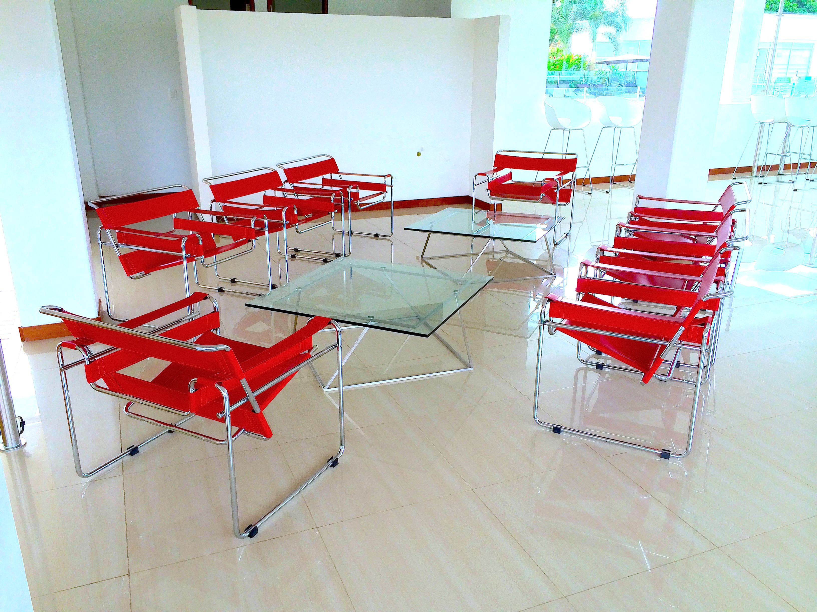 Une salle de conférence dotée d’une table en verre, entourée de chaises rouges, de grandes fenêtres et offrant une vue sur l’extérieur.
