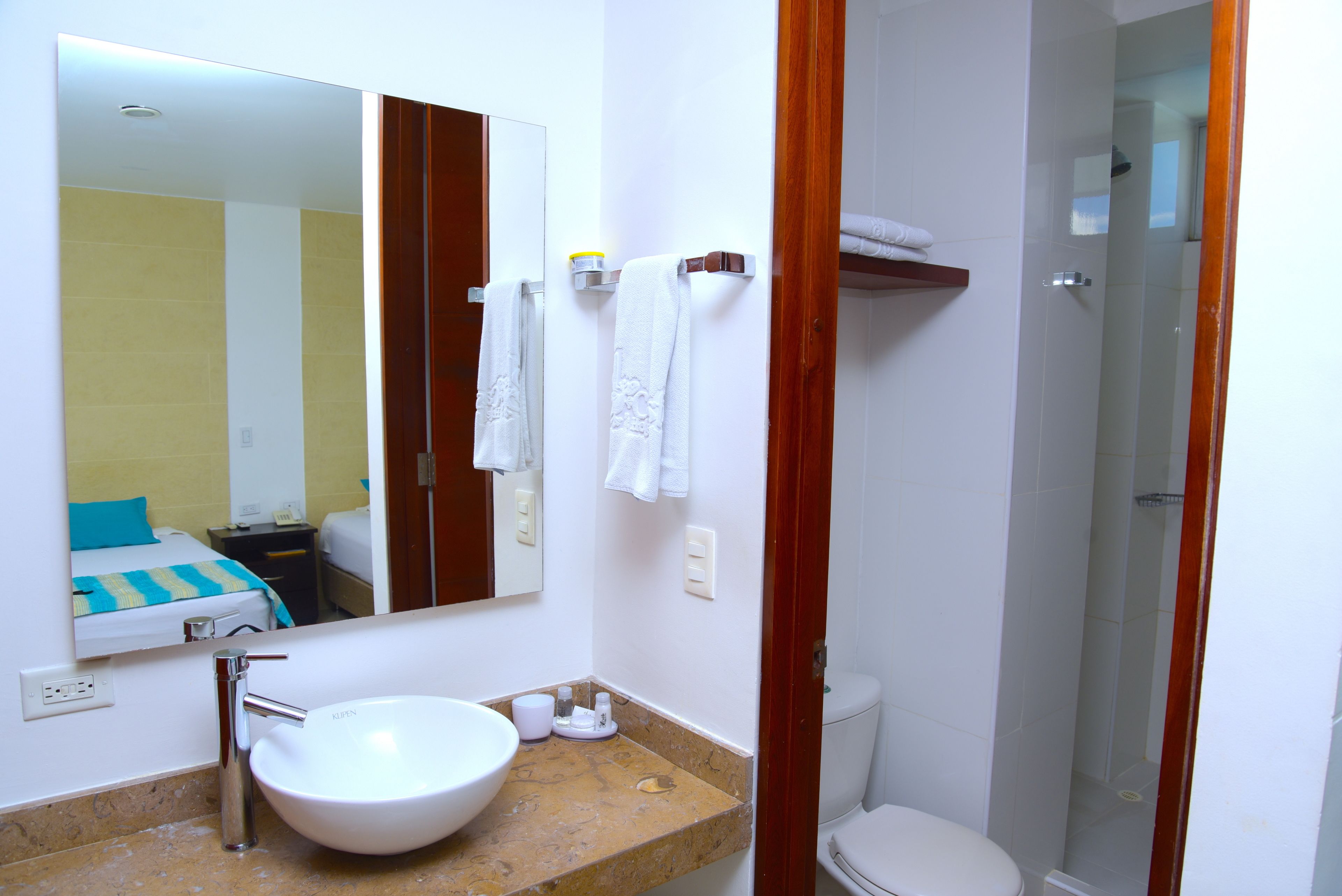Un baño con un lavabo blanco, espejo y perchero para toallas.