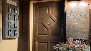 A wooden door with a geometric pattern, a potted plant, and a sign with the name 'Santa Colas' on the wall. - Casa Rural Santu Colás (Cangas de Onis)