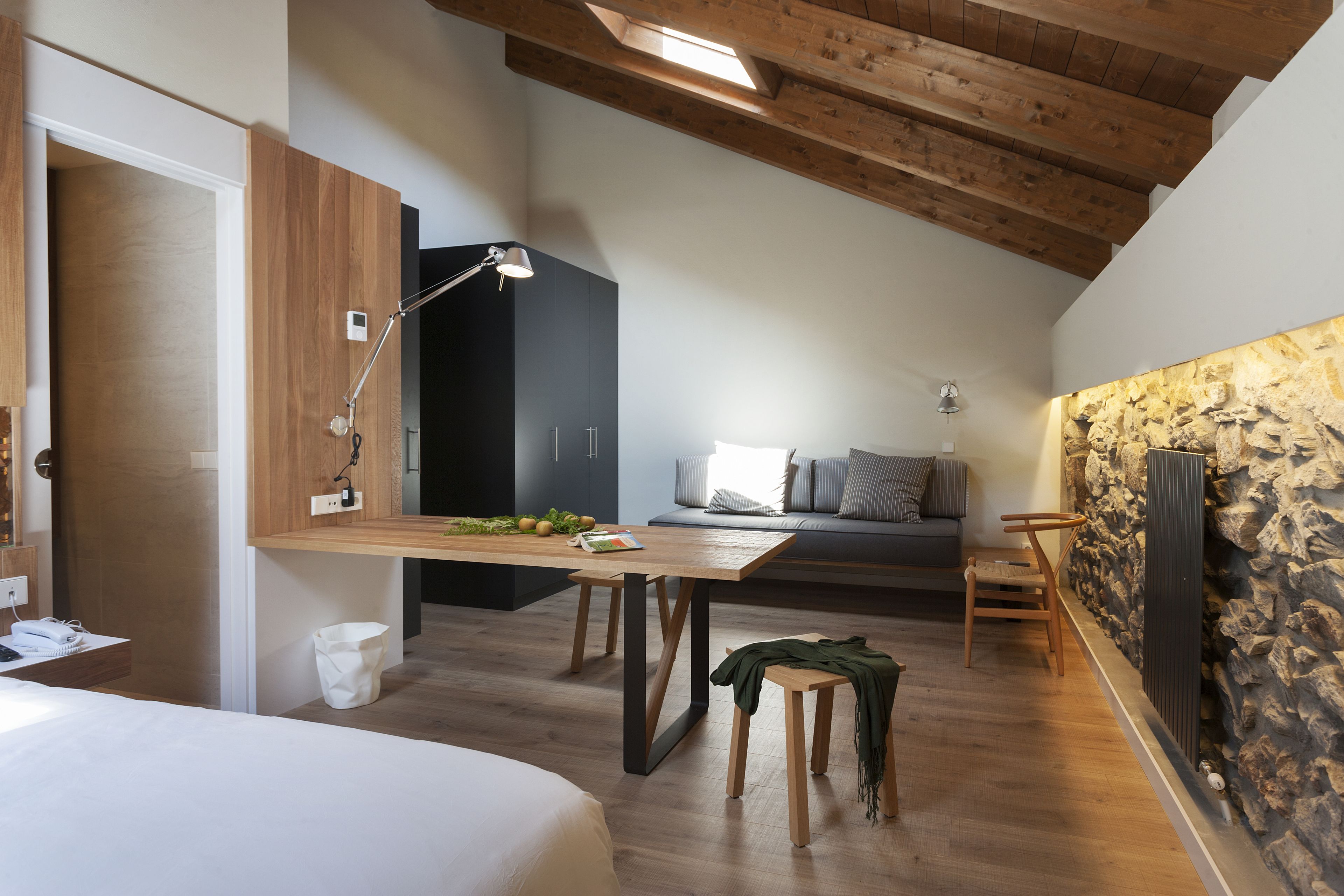 Une pièce moderne avec un plafond en bois, une table à manger avec des chaises, un canapé et un mur décoratif en pierre.