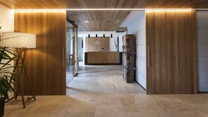 A modern reception area with wooden paneling, a reception desk, and a potted plant. - Palacio de Yrisarri by IrriSarri Land (Igantzi)