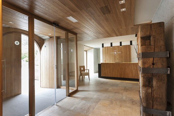 A reception area with a wooden reception desk, a chair, and a glass door leading to another room.