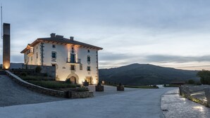 A large, white building with a balcony, surrounded by a stone pathway and a view of a mountain range. - Palacio de Yrisarri by IrriSarri Land (Igantzi)