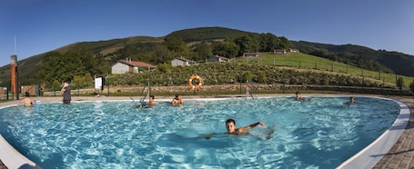 Una piscina al aire libre de temporada, sombrillas