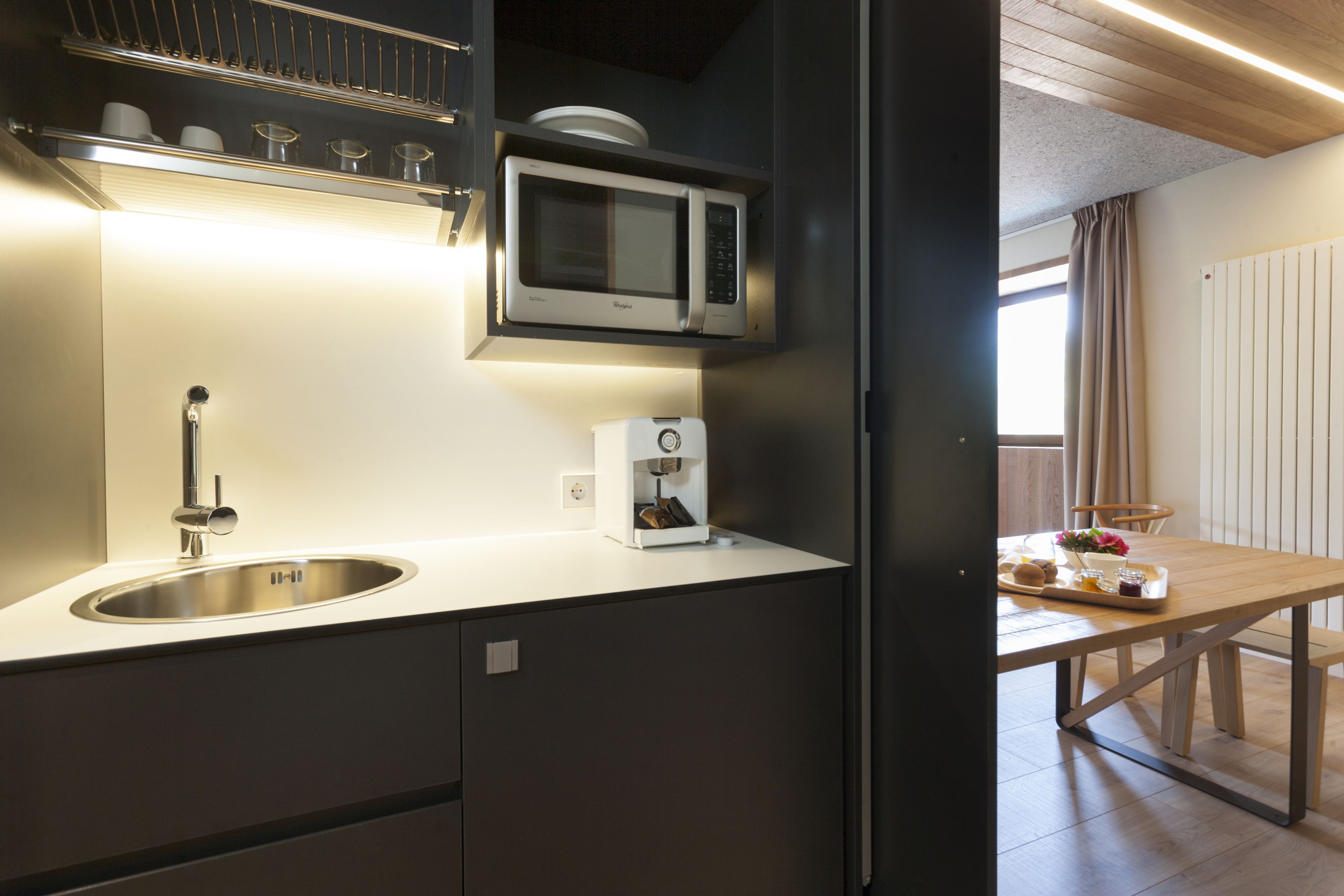 A modern kitchen with a built-in microwave, a coffee machine, and a sink.