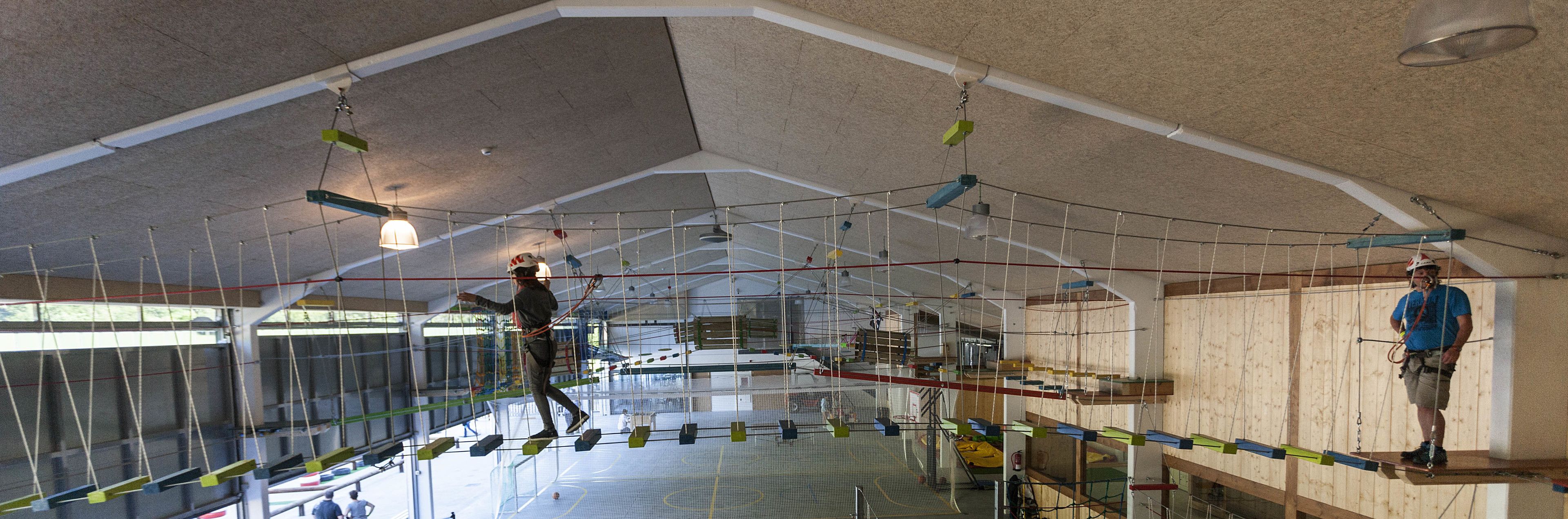 Instalación de escalada en interiores con varias paredes y redes de seguridad.