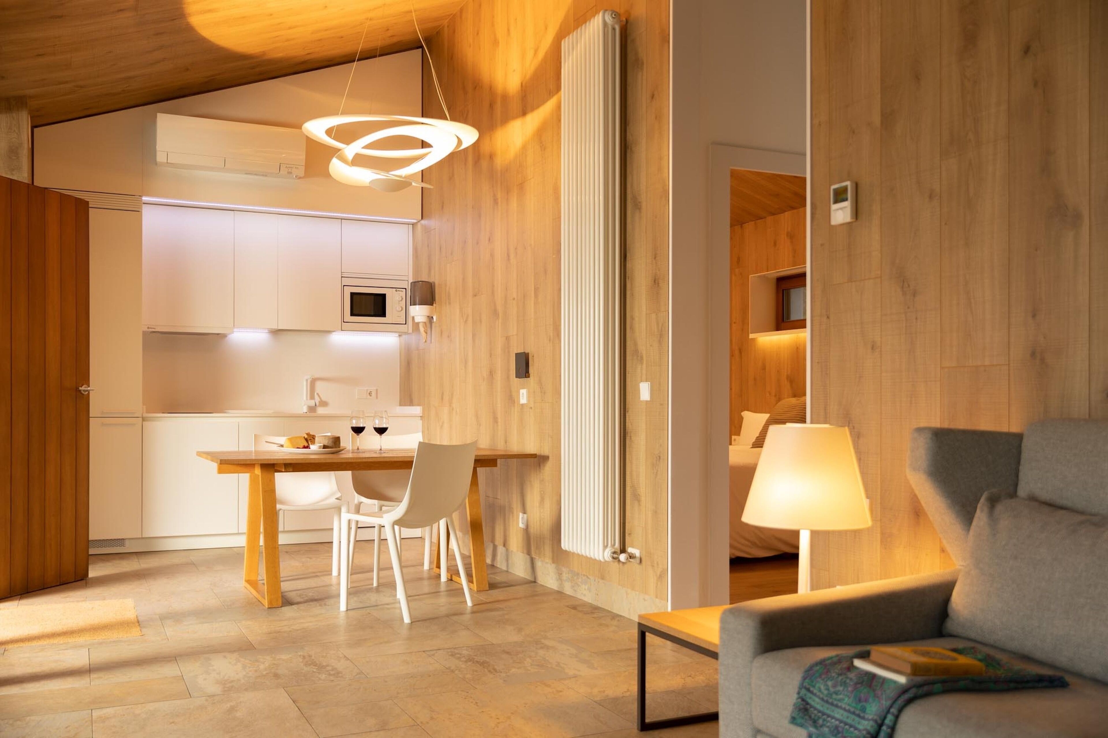 Una cocina moderna con armarios blancos, una mesa de comedor de madera y una lámpara colgante.