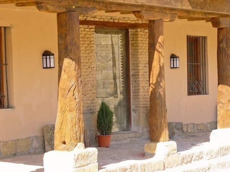 Un bâtiment aux murs de pierre, aux poutres en bois et avec une plante en pot dans l’entrée.