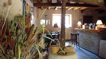 Un interior rústico con una mesa de piedra, vigas de madera y una zona de bar con botellas.