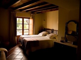 Un dormitorio con dos camas, un ventanal grande y techo de madera.