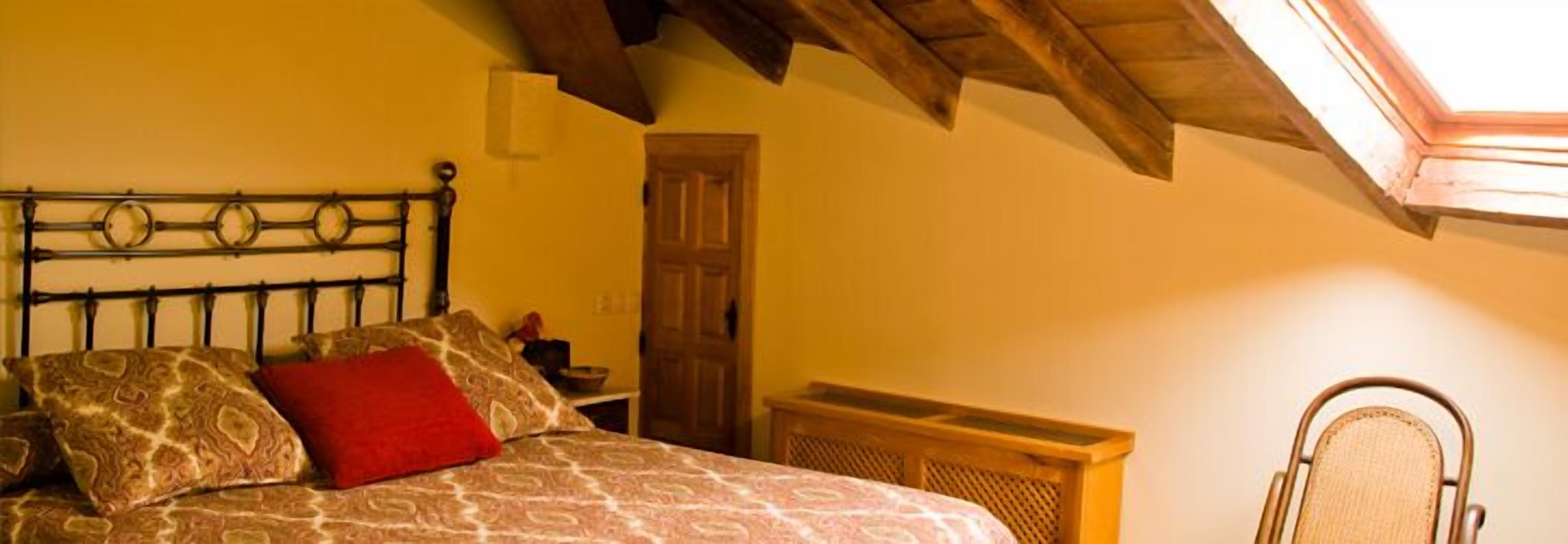 A bedroom with a bed, a wooden door, and a window.