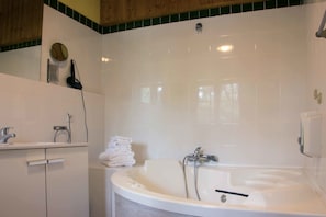 A bathroom with a white bathtub, a sink, and a mirror. There are towels stacked on a shelf. - Xalet de Prades (Prades)