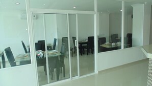 A dining area with a glass partition, black chairs, and a table set for four. - Karin Hotel (Riohacha)