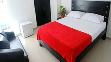 Un dormitorio ordenado con cama, un escritorio pequeño y un armario.