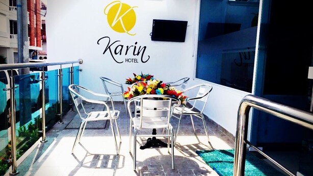 A modern hotel room with a glass balcony, a table with chairs, and a floral centerpiece. - Karin Hotel (Riohacha)