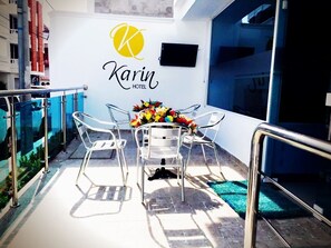 A modern hotel room with a glass balcony, a table with chairs, and a floral centerpiece. - Karin Hotel (Riohacha)