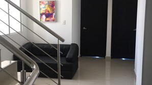 A modern interior with a staircase, a black sofa, and two closed doors. - Karin Hotel (Riohacha)