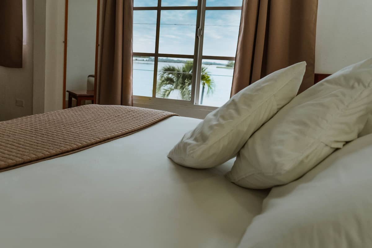 Una habitación de hotel con una cama, vista al mar y una ventana con cortinas.