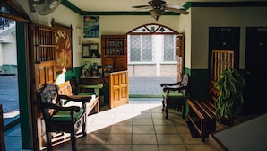 Una habitación con un banco de madera, un ventilador, un ventilador de techo, una ventana y una puerta.