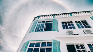 Un edificio blanco con contraventanas verdes y numerosas ventanas.