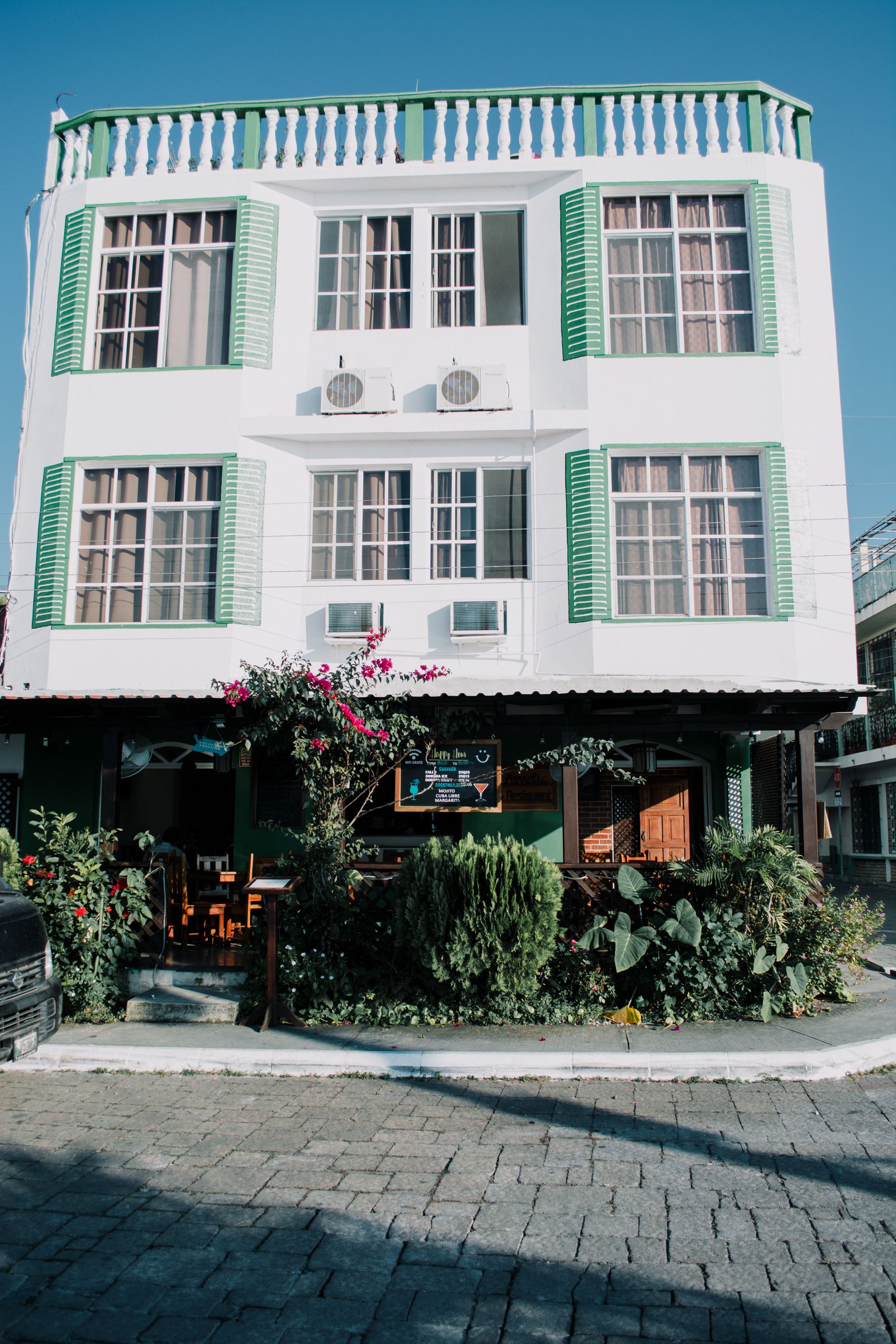 Um edifício de dois andares com persianas verdes e uma varanda.