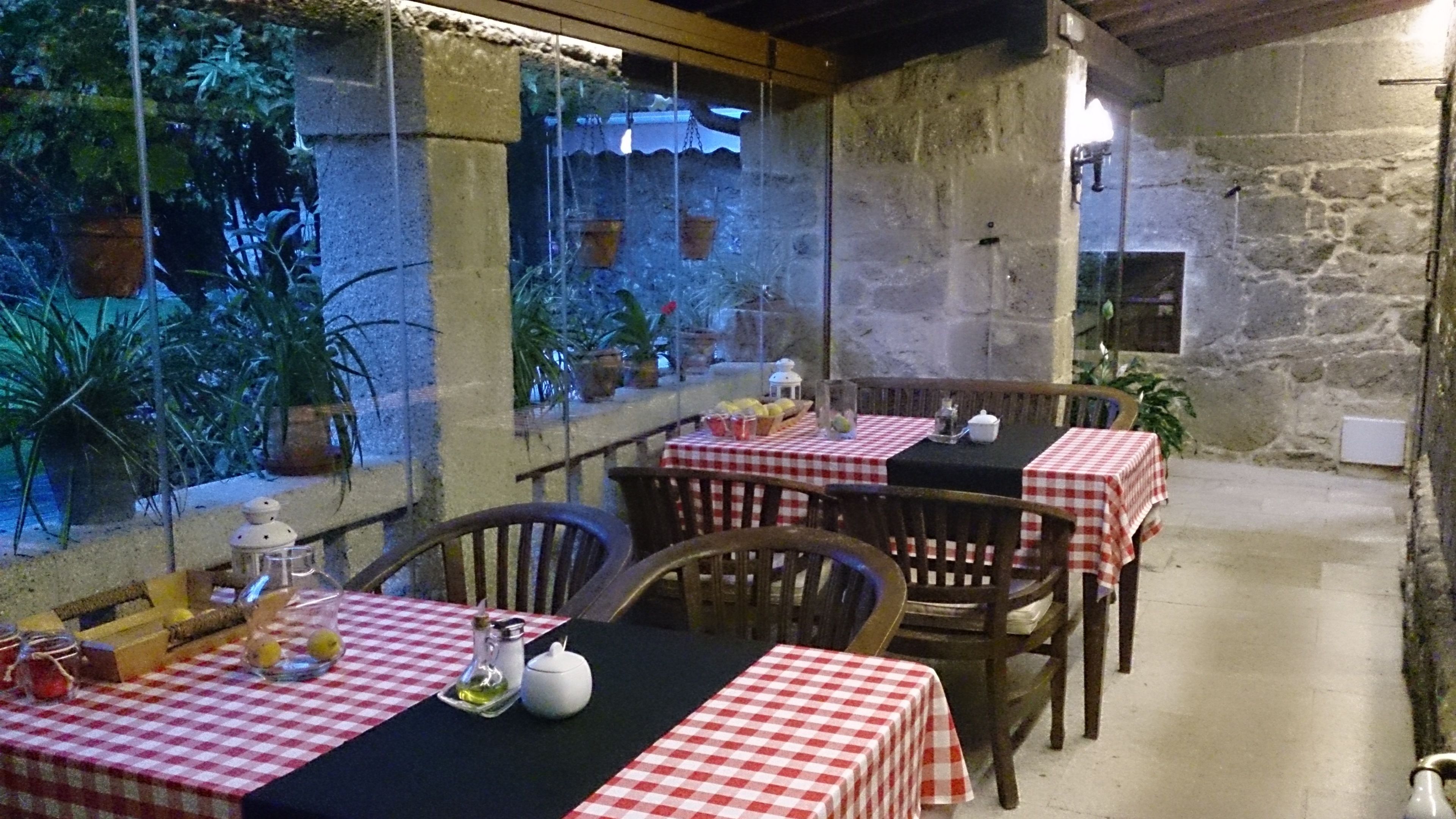 An outdoor dining area with checkered tablecloths, wooden chairs, and potted plants.