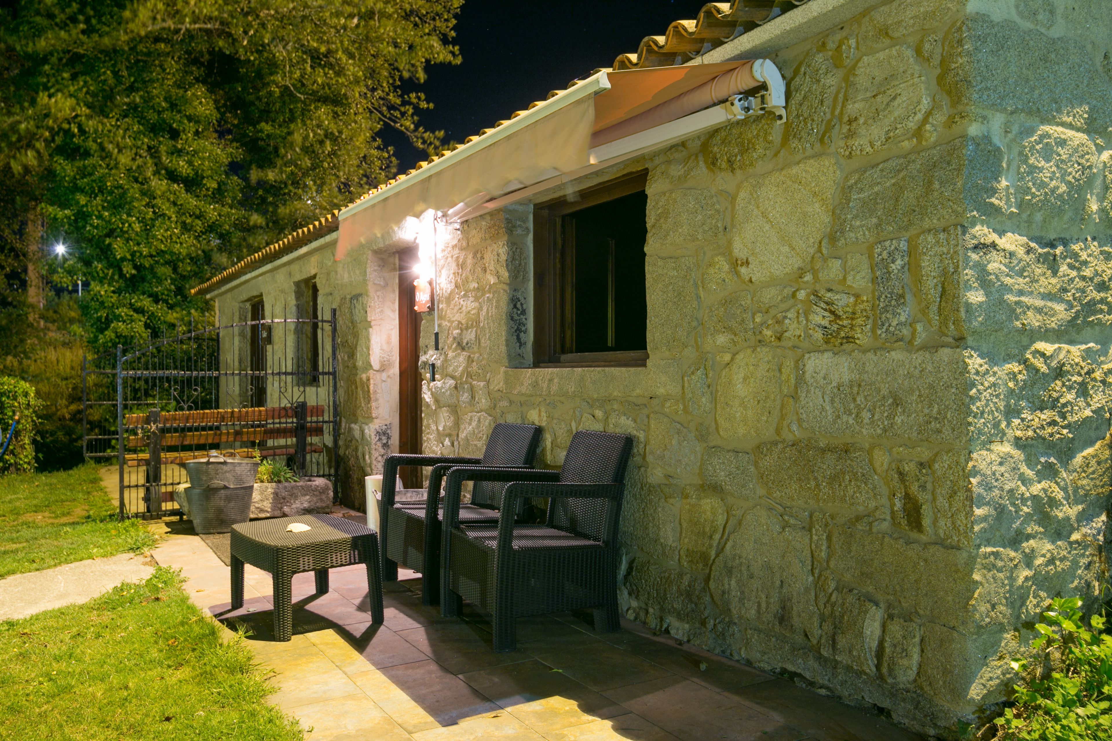Un bâtiment en pierre doté d’un patio aménagé avec des meubles en osier et une table.