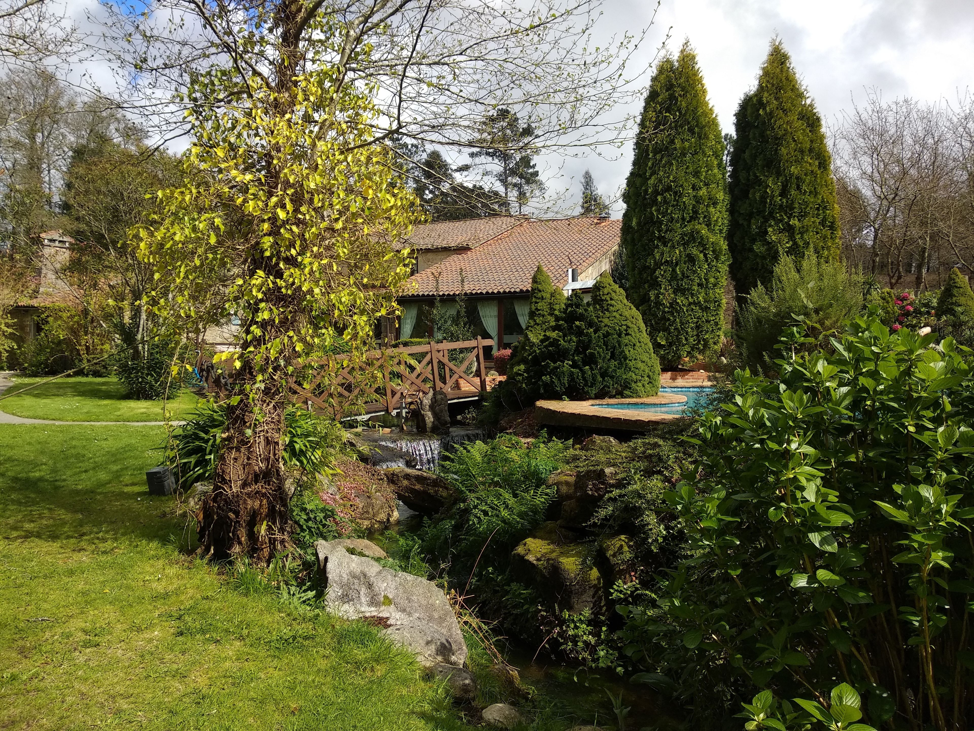 Ein Haus mit Garten, einer Holzbrücke und einem Schwimmbecken.