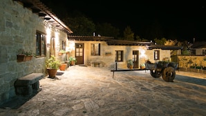 A stone building with a courtyard, potted plants, and a cart. - Aldea Os Muiños (Rianxo)