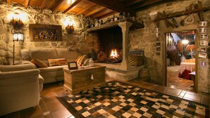 A cozy room with a stone fireplace, a checkered rug, and a sofa. - Aldea Os Muiños (Rianxo)