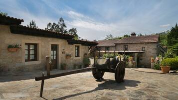 A stone building with a rustic exterior, a cart in front, and potted plants around.