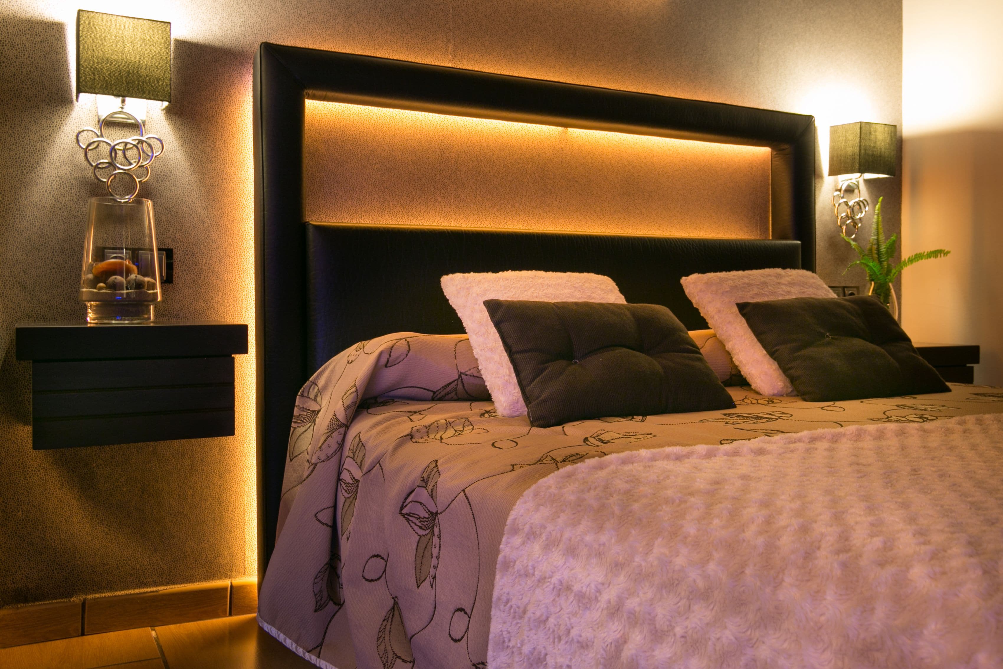A neatly made bed with a patterned bedspread, two pillows, and a fluffy white throw.