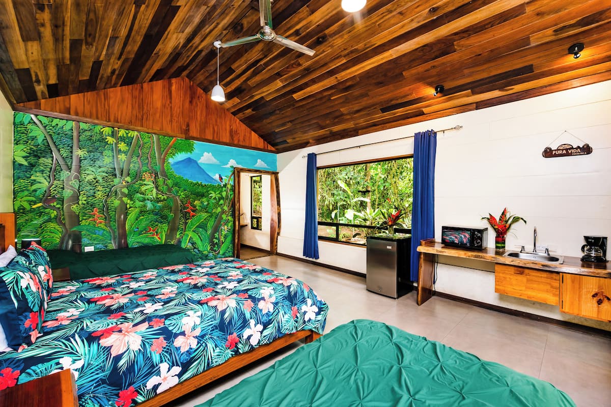 Un dormitorio con cama, escritorio y ventana con cortinas.