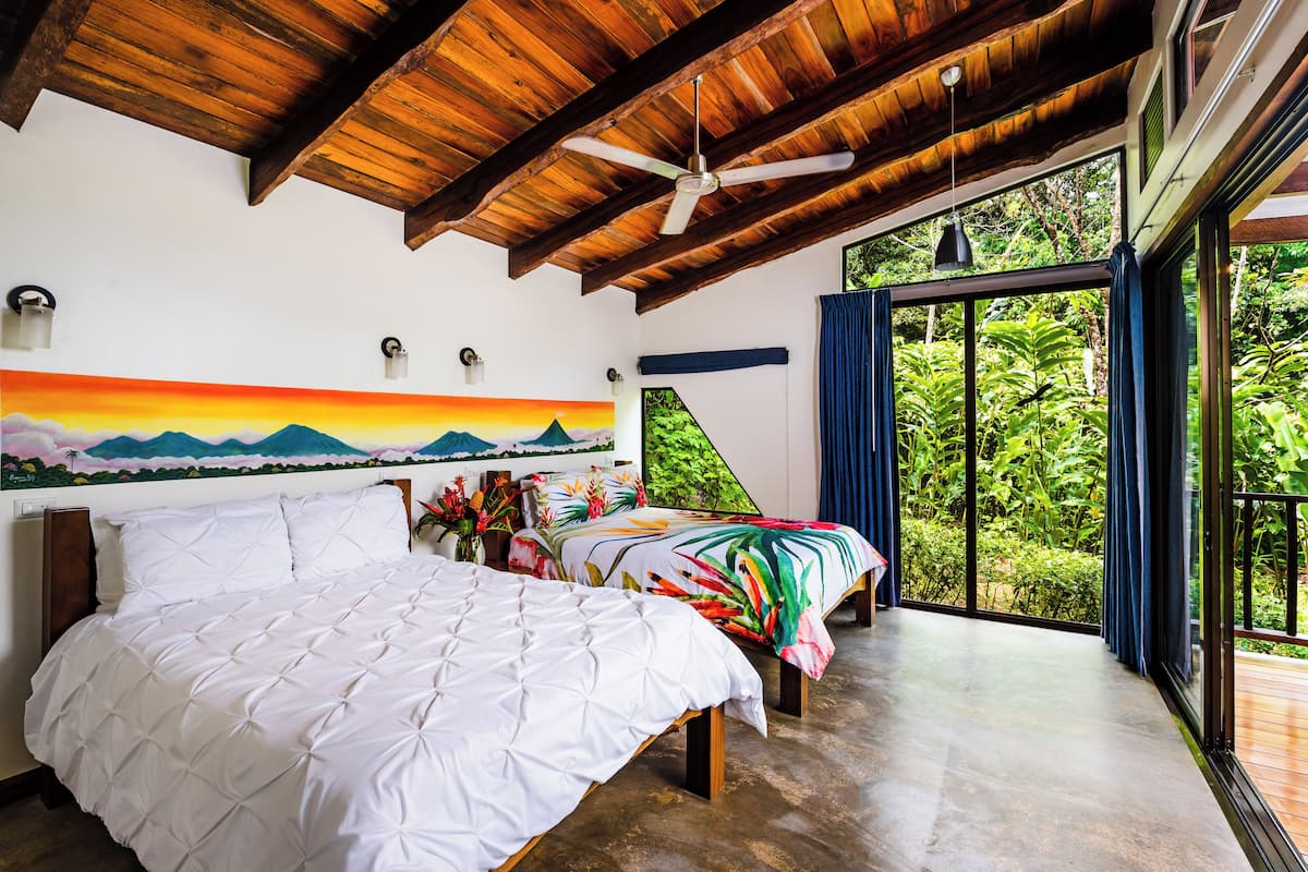 Un dormitorio con una cama grande, una cama más pequeña y una pintura de un atardecer.