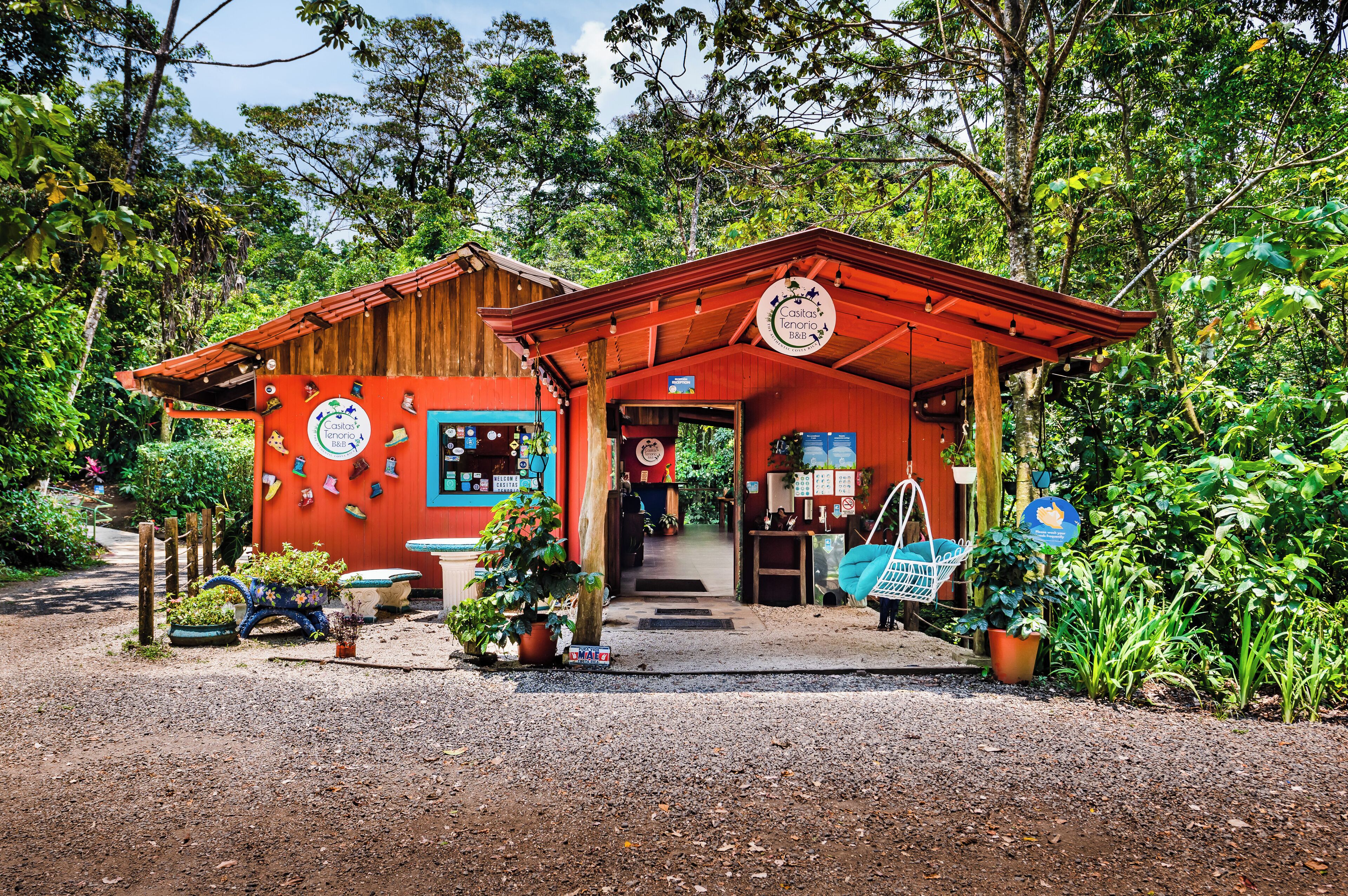 A rustic wooden building with a red facade, a porch, and a sign indicating it is a B&B.