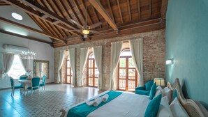 A spacious bedroom with a large bed, a dining area, and a chandelier. - Hotel Casa Tere (Cartagena)