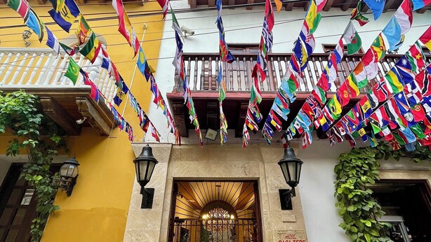 A building facade with multiple balconies and a variety of international flags displayed. - Hotel Casa Tere (Cartagena)