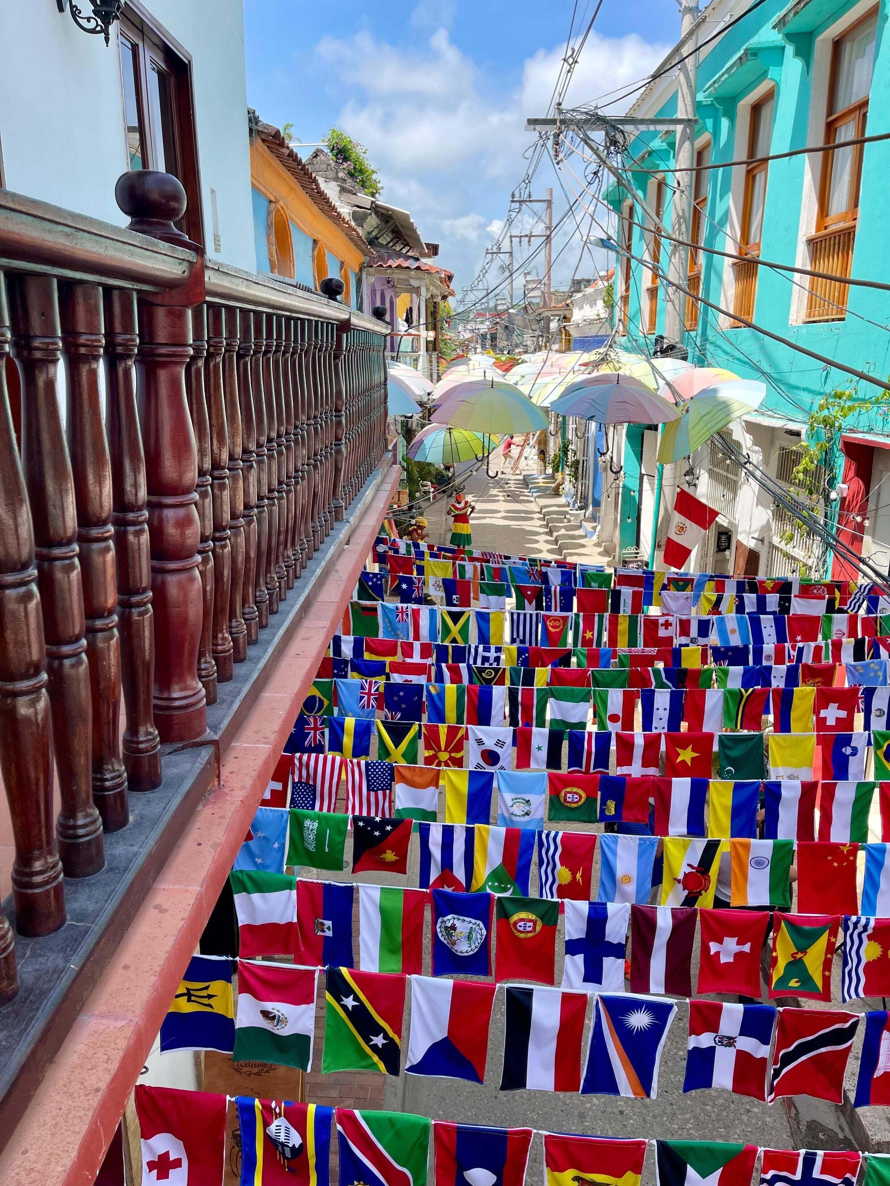 Une rue où des drapeaux colorés sont accrochés à la balustrade.