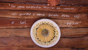 A wooden table with a mosaic sun design and a quote in Portuguese.