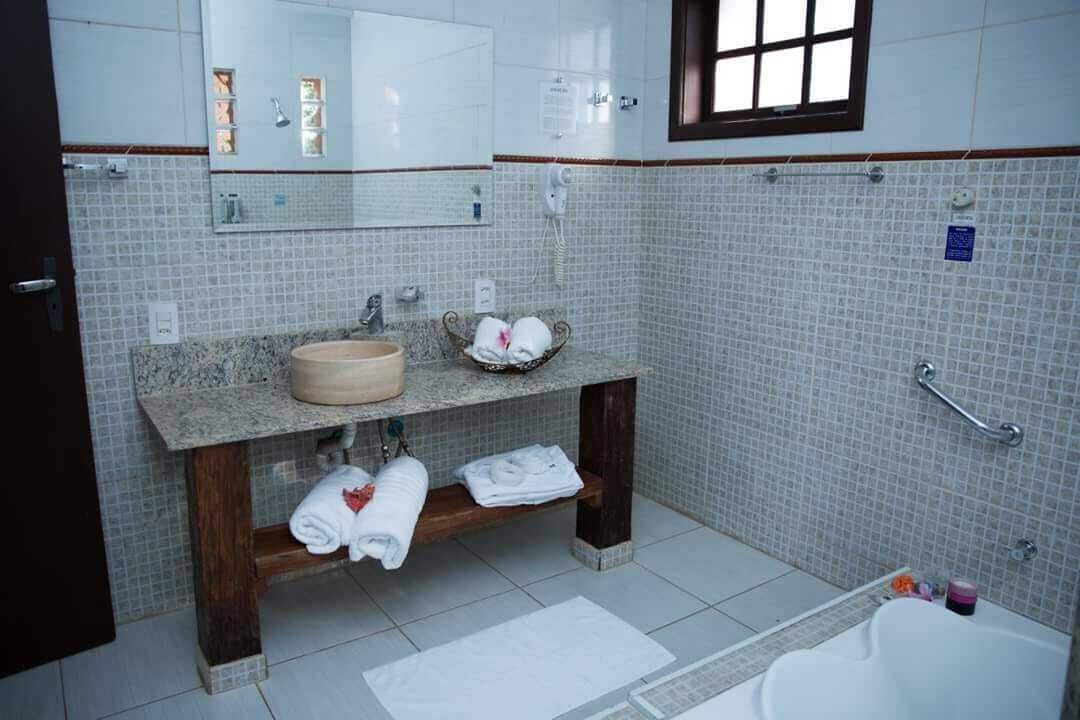 Uma casa de banho com lavatório de mármore, espelho, porta-toalhas e banheira.